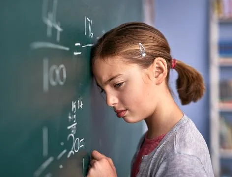 What did I do wrong. an elementary school girl pressing her head against the Stock Photos