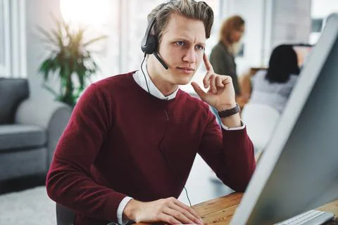 What seems to be the problem. a young man using a headset and computer in a Stock Photos