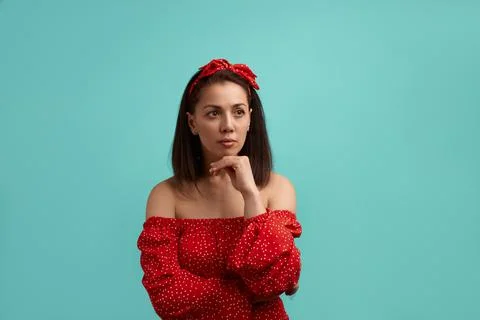 What should I do. Portrait of thoughtful young woman in red dress keeps hand  Stock Photos