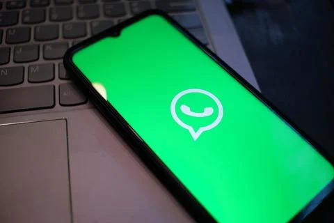 WhatsApp Integration: Smartphone Displaying WhatsApp App Logo on a Laptop Stock Photos