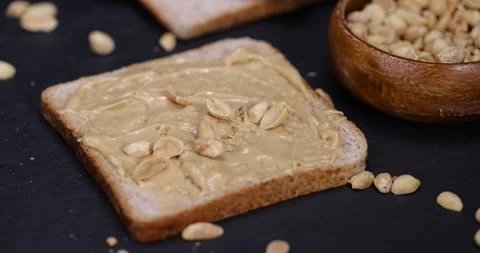 Wheat bread with bran and soft peanut butter, peanut butter on a piece of bread Stock Footage 310797215