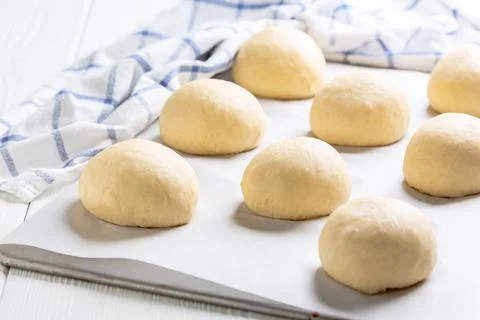 Wheat buns rising on a baking sheet. Stock Photos