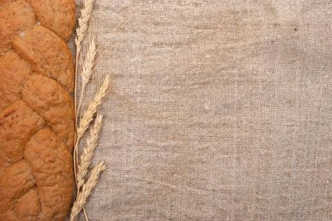Wheat ears and bread on burlap background Stock Photos