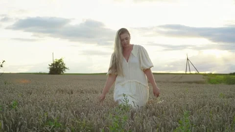 The wheat field becomes a place of rest and reflection for the woman. Video stock 250602919