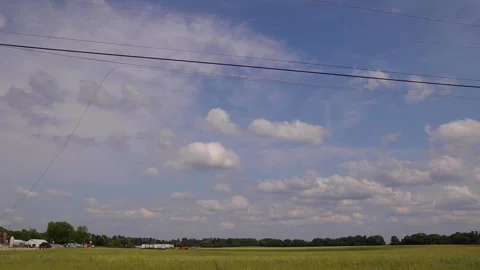 A wheat field on a cloudy blue sky day with traffic in the distance. Stock Footage 153571222