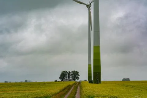 A wheat field with two large wind power towers in the background. Dark clouds Stock Photos