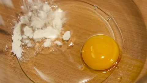 Wheat flour is added to plate with egg. Slow motion Stock Footage 76166736