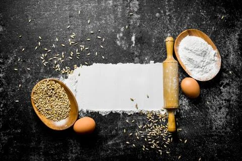 Wheat flour with egg, rolling pin and grain. Stock Photos