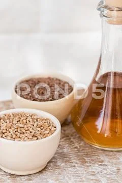 Wheat grains in wooden bowl and oil in decanter Stock Photos