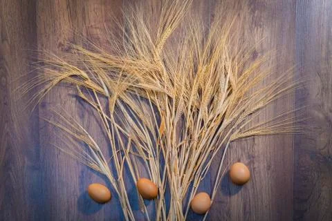 Wheat spread over a table with brown eggs Stock Photos