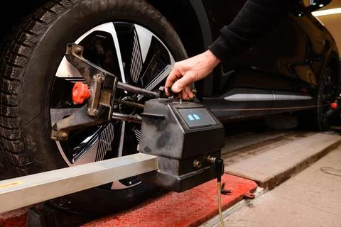 Wheel alignment and alignment on the car service platform. A technician works 库存照片