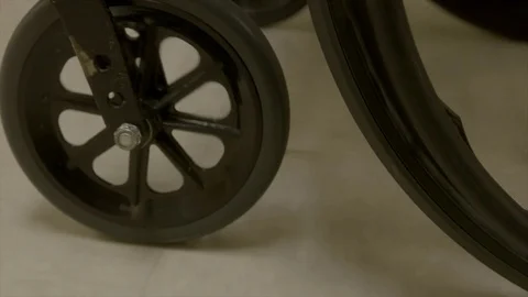 Wheel chair wheels rolling down hospital hallway Stock Footage