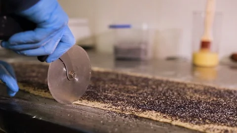 Wheel knife cuts a great sheet of dough with poppy seeds. Close-up Stock Footage 106468619