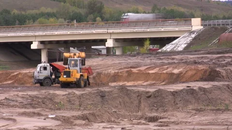 The wheel loader digs and fills the earth in the truck Stock Footage 47928757