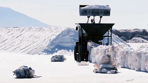 Wheel Loader Dumping Salt into Hopper to Fill Big Bags in Salinas Grandes - 4K Stock Footage 340992459