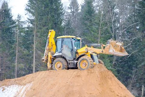 Wheel loader Excavator with backhoe unloading sand at eathmoving works in con Stock Photos