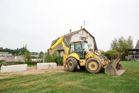 Wheel loader. Excavator install the foundation blocks into a trench. Retainin Foto stock