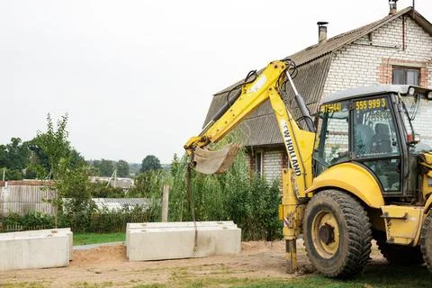 Wheel loader. Excavator install the foundation blocks into a trench. Retainin Stock Photos