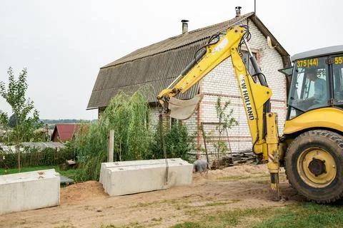 Wheel loader. Excavator install the foundation blocks into a trench. Retainin Stock Photos