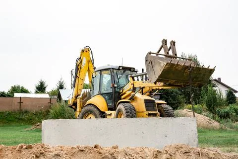 Wheel loader. Excavator install the foundation blocks into a trench. Retainin Stock Photos