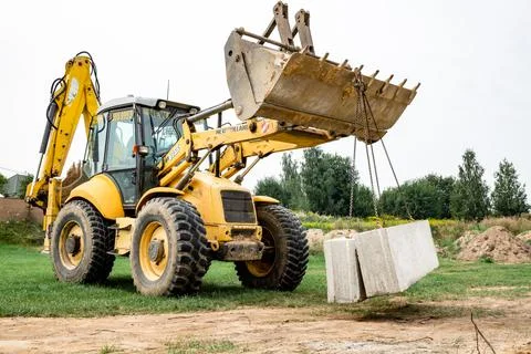 Wheel loader. Excavator install the foundation blocks into a trench. Retainin Foto stock