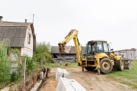 Wheel loader. Excavator install the foundation blocks into a trench. Retainin Foto stock