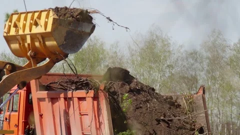 Wheel loader excavator loading construction garbage in a dump truck Stock Footage