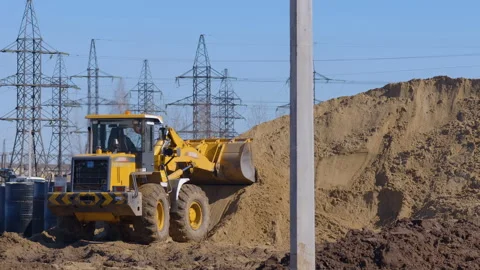 Wheel loader, with its large bucket in front, moves large amounts of land  Stock Footage 147633123
