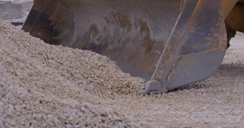 Wheel loader, with its large bucket in front, moves large amounts of gravel Stock Footage 161959330