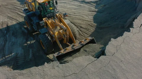Wheel loader scoops up rubble with bucket from pile of sand Stock Footage 165387943
