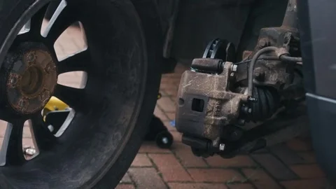 Wheel positioning for installation after brake repair with mechanic lifting tire Stock Footage 335369034