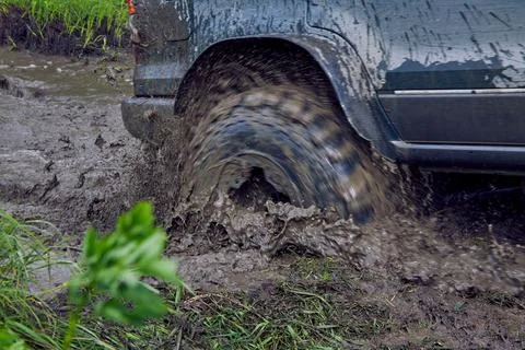Wheel of the off road rotates in a puddle of mud Stock Photos