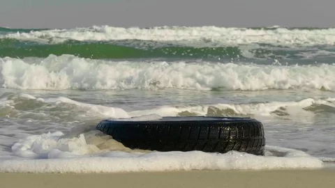 The wheel on the sandy shore is washed by waves. Stock Footage 80576965