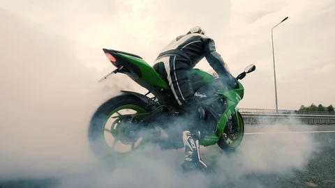 Wheel of sport motorbike starting to spin at asphalt and tire burnout with lots Stock Footage