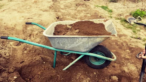 Wheelbarrow with ground on gardering. Loading soil into a construction cart. Stock Footage 218546355