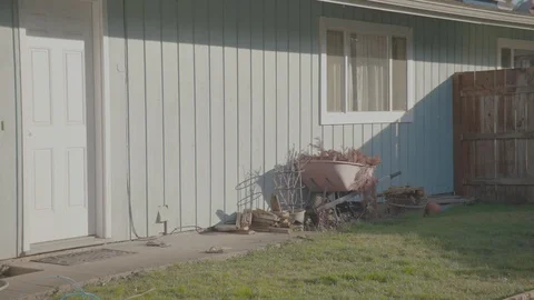 A wheelbarrow leaning on the side of a house Stock Footage 103823424