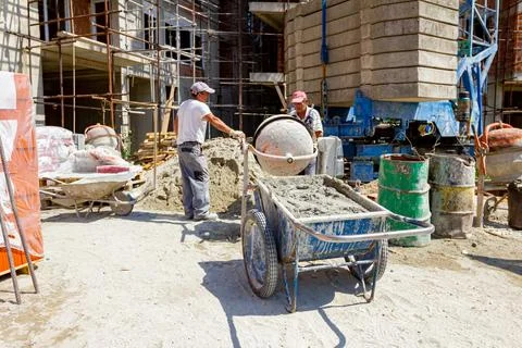 Wheelbarrow with mortar and empty cement mixer machine placed on constructi.. Stock Photos