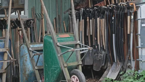 Wheelbarrows and shovels by tool shed in garden Stock Footage 115841653