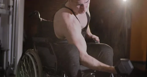 Wheelchair user doing strength exercises with dumbbells. Lens flare. Stock Footage 146764798