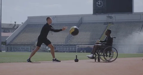 Wheelchaired athlete and trainer throwing medicine ball Stock Footage 116765776