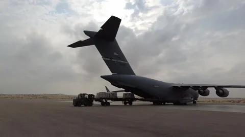 Wheeled loader loading pallet of humanitarian aid onto U.S. C-17 Globemaster Stock Footage 257666347