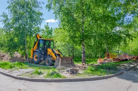 A wheeled universal backhoe loader digs a trench Stock Photos
