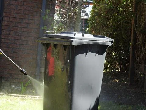 A wheelie bin being jet washed Stock Photos