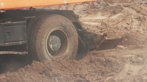 Wheels in the mud and clay of an excavator that digs a hole, close-up. Industry Stock Footage 253472417