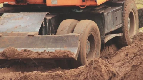 Wheels in the mud and clay of an excavator that digs a hole, close-up. Industry Stockbeeldmateriaal 254064796