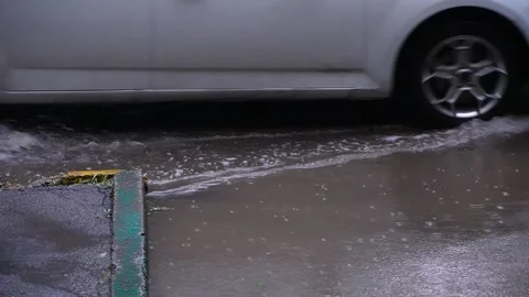 The wheels of a white car drive through a deep puddle during the rain Stock Footage 195213434