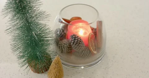 When breeze sweeps speckled countertop, red candle flame is flickering, casting Stock Footage 344225956