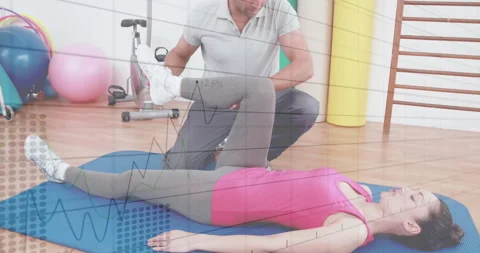 When checking leg alignment, physio trainer raising and bending client's leg on Stock Footage 310743613