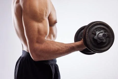 When form meets function. a man holding dumb bells against a studio background. Stock Photos