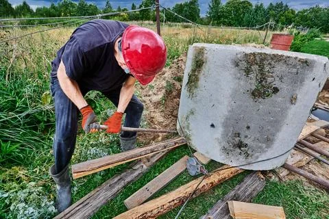 When installing septic tank, builder pushes one concrete ring onto another .. Stock Photos